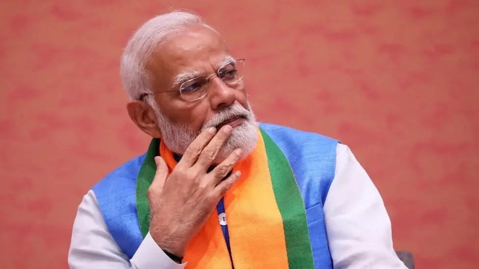 కాషాయ, ఆకుపచ్చ కండువాతో ఆలోచనలో మునిగి గడ్డంపై చేయి ఉంచిన ప్రధాని నరేంద్ర మోదీ