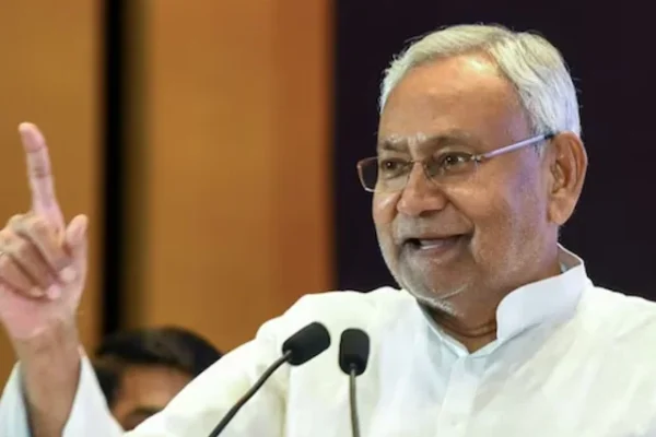 తెల్లని కుర్తా ధరించి, మైక్రోఫోన్ల ముందు చూపుడు వేలు ఎత్తి మాట్లాడుతున్న నితీష్ కుమార్