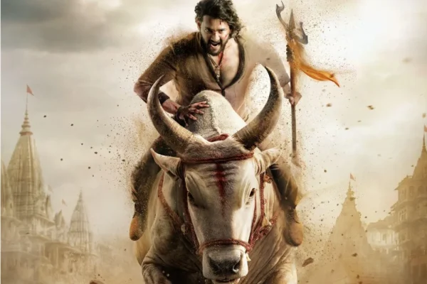 త్రిశూలం ఎత్తిపట్టిన యోధుడు ఎద్దుపై దూసుకొస్తుండగా వెనుక దుమ్ములో ఆలయ గోపురాలు కనిపిస్తున్న సినిమా పోస్టర్